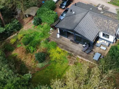 Luchtfoto van de vergaderbungalow met terras, tuin en eigen parkeerplaats midden in het bos